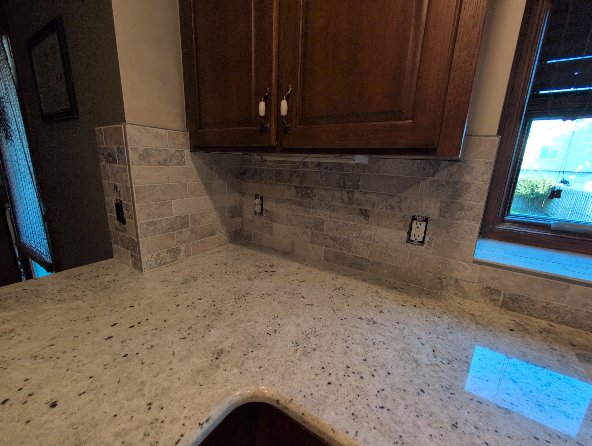 Travertine tile inside corner detail in Omaha kitchen with dark cabinets